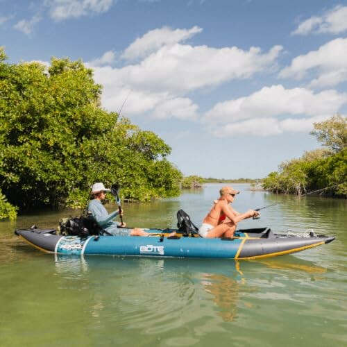 Two people fishing from an inflatable kayak in a mangrove area.