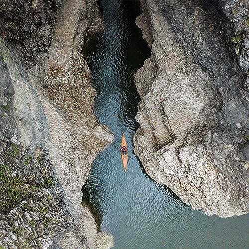 Kayaker paddling through a narrow rocky passage.