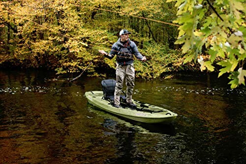 Person fishing from kayak on a river surrounded by autumn trees