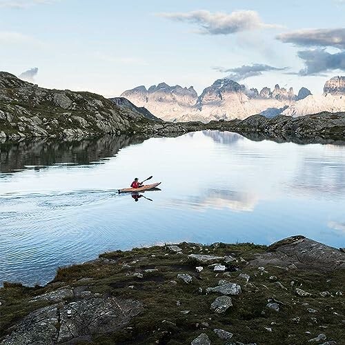 Person kayaking on a tranquil mountain lake.