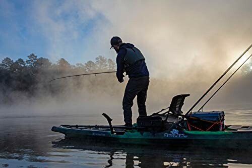 Person fishing from a kayak on a misty lake at sunrise.