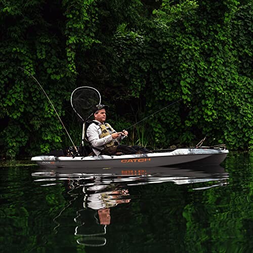 Man fishing from a kayak on a river surrounded by greenery.