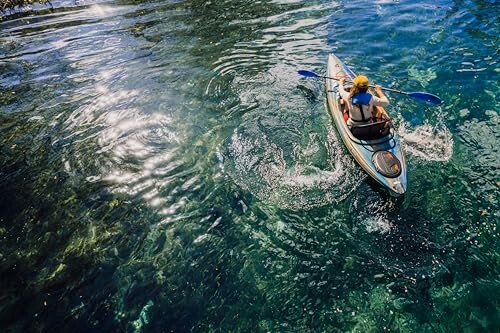 Person kayaking on clear water with ripples